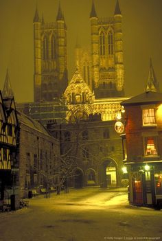 an old city street is lit up at night with lights shining on the buildings and cathedrals in the background