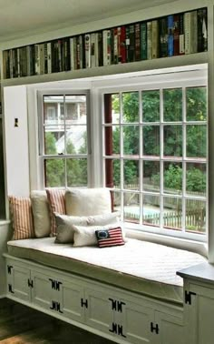 a window seat in front of a bookshelf filled with books