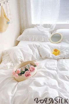 a bed with white sheets and pink flowers on the bottom, next to a mirror