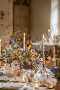 the table is set with candles, flowers and glassware for an elegant dinner party