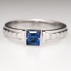 a white gold ring with a blue sapphire in the center and two thin bands around it