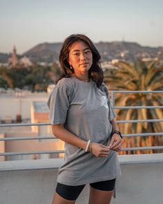 a woman standing on top of a roof next to a palm tree in the background