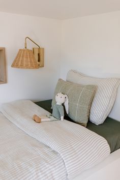 there is a stuffed animal on the bed with two pillows and a lamp in the corner