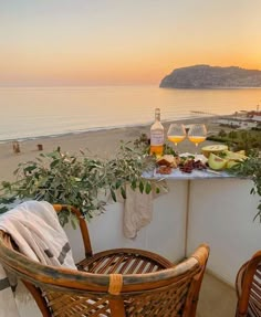 two wicker chairs sitting next to each other on top of a balcony near the ocean