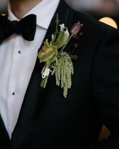 a man in a tuxedo with flowers and greenery on his lapel