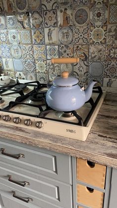 a stove top oven sitting inside of a kitchen next to a wall covered in tiles