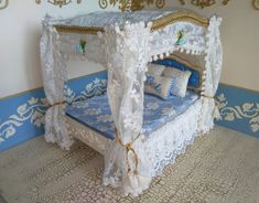 a bed made out of white lace with blue sheets and pillows on the bottom side