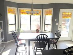 a dining room table with four chairs in front of two windows and a door leading to the outside