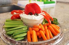 a plate with carrots, celery, broccoli and dip on it