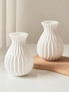 two white vases sitting next to each other on a table