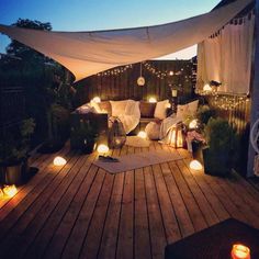 an outdoor deck with lights and pillows on it