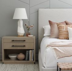 a bedroom with a bed, night stand and lamp on the side table in front of it