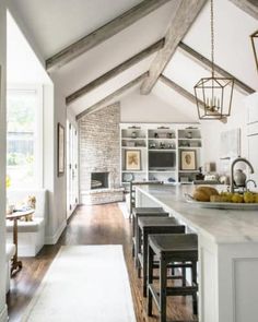 an open kitchen and living room with white walls, wood floors and exposed beams on the ceiling