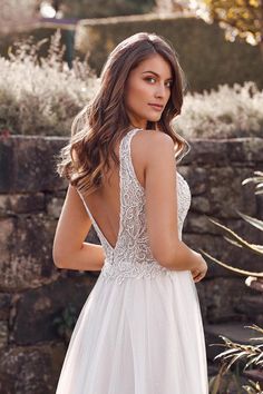 a woman in a white wedding dress looking back with her hand on her hip,