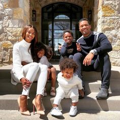 a group of people sitting on steps in front of a door with their arms around each other