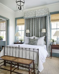 a bedroom with a bed, two lamps and a bench in front of the window