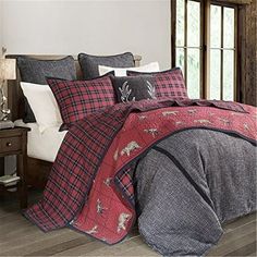 a bed with red and black plaid comforter, pillows and blankets on top of it