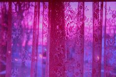 the window is covered with pink sheer curtains