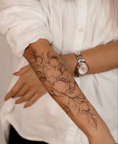 a woman's arm with flowers on it and a watch around her wrist,