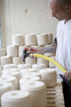 a man in white shirt holding a yellow hose next to rolls of toilet paper