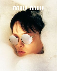 a woman wearing sunglasses laying in a bubble filled bathtub with foam around her eyes