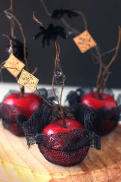 three red apples are sitting on a wooden board with black netting and twine around them