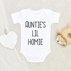 a baby's bodysuit with the words auntie's lil homie on it next to a teddy bear