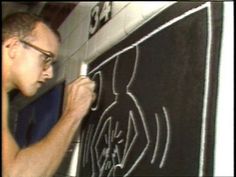 a man writing on a blackboard with white chalk