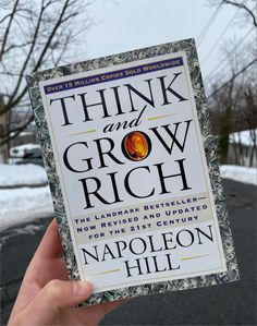 a person holding up a book about think and grow rich