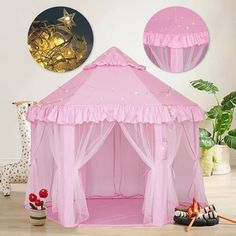 a pink play tent sitting on top of a wooden floor next to a potted plant