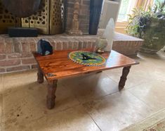 a wooden table sitting on top of a tiled floor next to a fire place in a living room