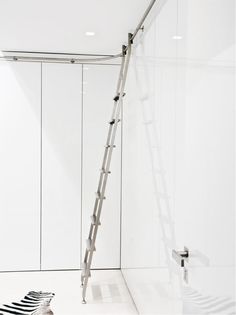 a ladder leaning against the wall in a white room with black and white stripes on the floor