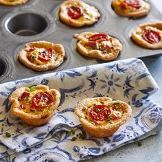 mini tarts with tomatoes and cheese on top in a muffin tin next to a baking tray