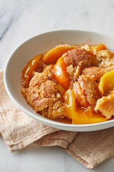 a close up of a bowl of food with meat and fruit in it on a table