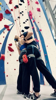 two climbers hugging each other in front of a climbing wall