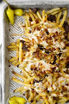 a tray filled with french fries covered in cheese and toppings next to some green peppers