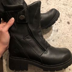 someone is holding up their black boots to show the side zippers on it's sides