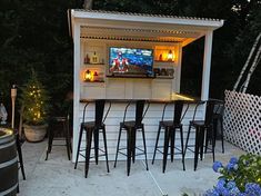 an outdoor bar with stools and television