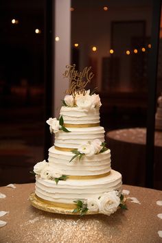 a wedding cake with white flowers and gold trimmings on a table in a restaurant