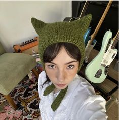 a woman wearing a knitted hat and green scarf with an animal head on it