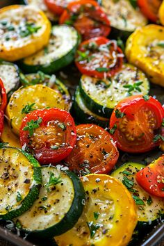 a pan filled with sliced up tomatoes and zucchini on top of a wooden table