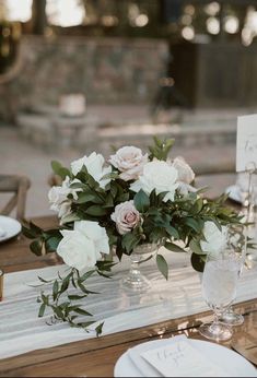 the table is set with white flowers and greenery