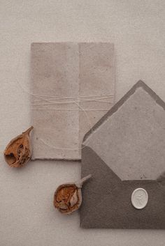 an envelope with a coin on it next to two pieces of paper and some dried flowers