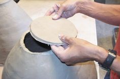 a person is making something out of a large gray pot with one hand on it