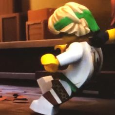 the lego man is wearing a green and white hat, black pants, and brown shoes