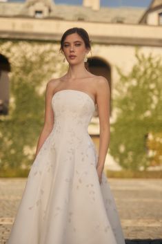 a woman in a white wedding dress standing outside