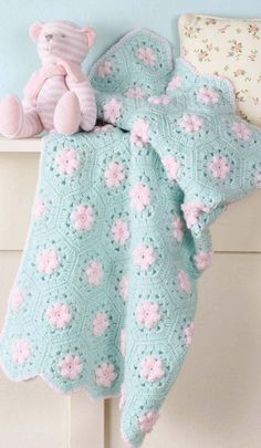 a pink teddy bear sitting on top of a bed next to a blanket and pillow