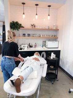 a woman is getting her hair done in a beauty salon while another person sits on the chair