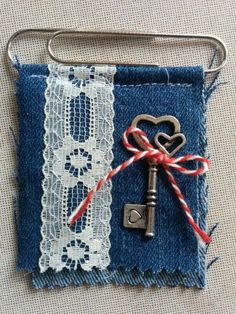 an old key is attached to a piece of fabric with a lace and red ribbon