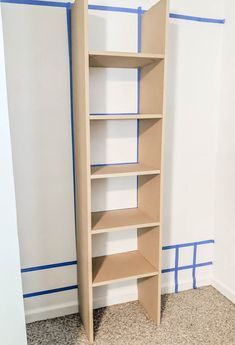 an empty book shelf in the corner of a room with blue tape on the walls